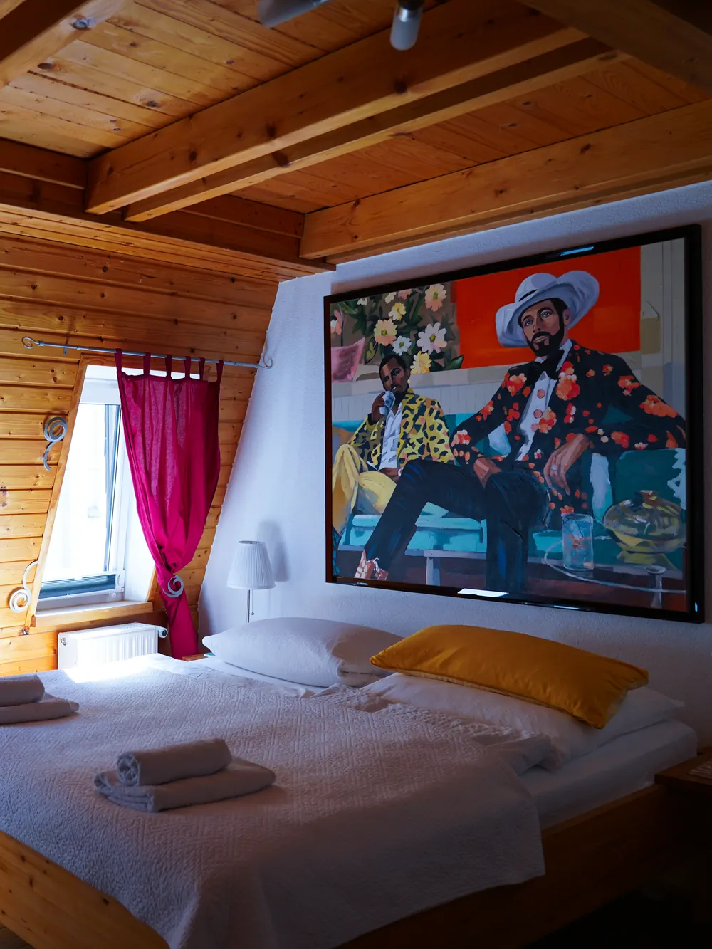 Doppelzimmer in der Mansarde mit Holzdecke und großem Gemälde über dem Bett