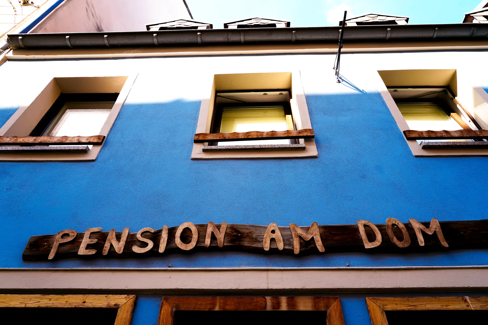Die blaue Fassade der Pension am Dom mit dem geschnitzten Holzschild über dem Eingang