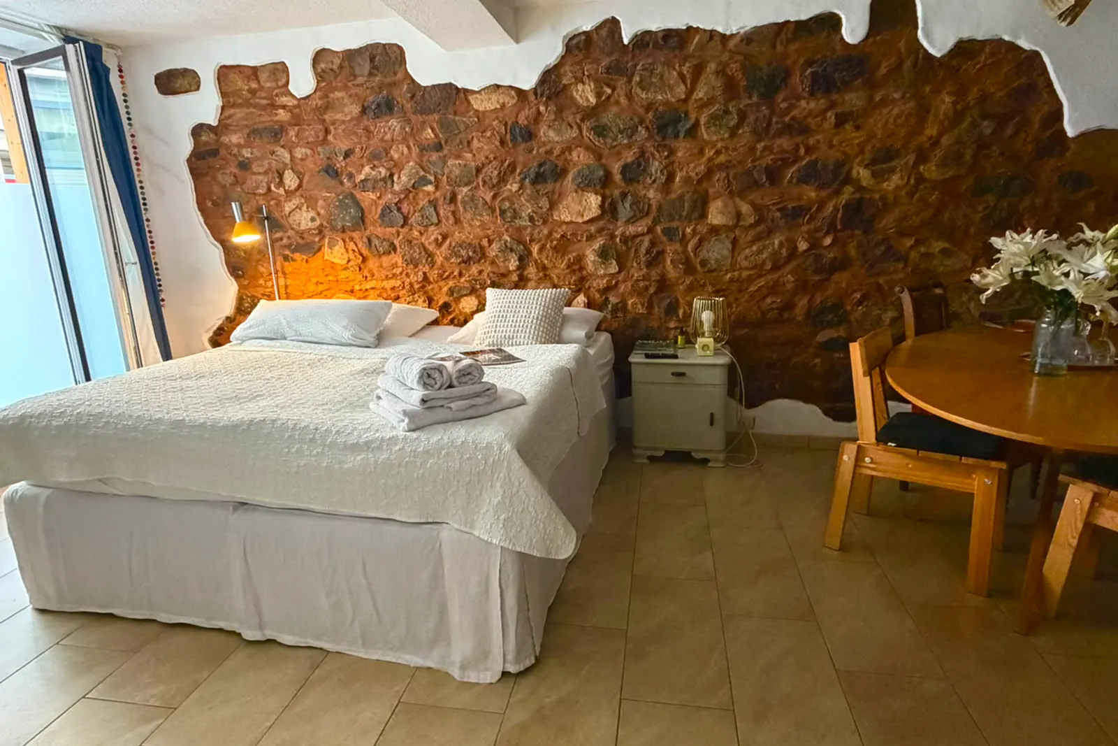 Die Ferienwohnung mit freigelegter Natursteinwand und großem Bett